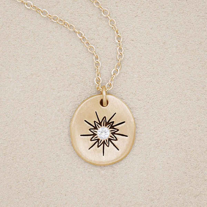 10k yellow gold sunburst diamond necklace on beige background