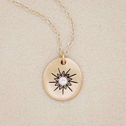 10k yellow gold sunburst diamond necklace on beige background