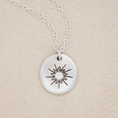 sterling silver sunburst diamond necklace on beige background