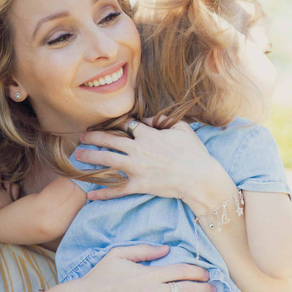 woman wearing her sterling silver sunburst diamond ring with a 3mm conflict free diamond and with her child