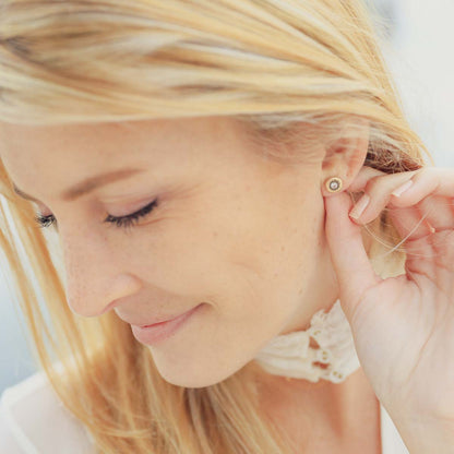 girl wearing pair of 10k yellow gold sunburst stud earrings with a matte-brushed finish with 3mm crystals 