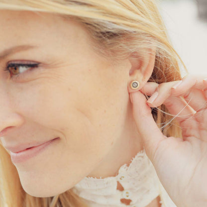 Girl wearing her 14k yellow gold sunburst stud earrings with a matte-brushed finish with 3mm crystals 