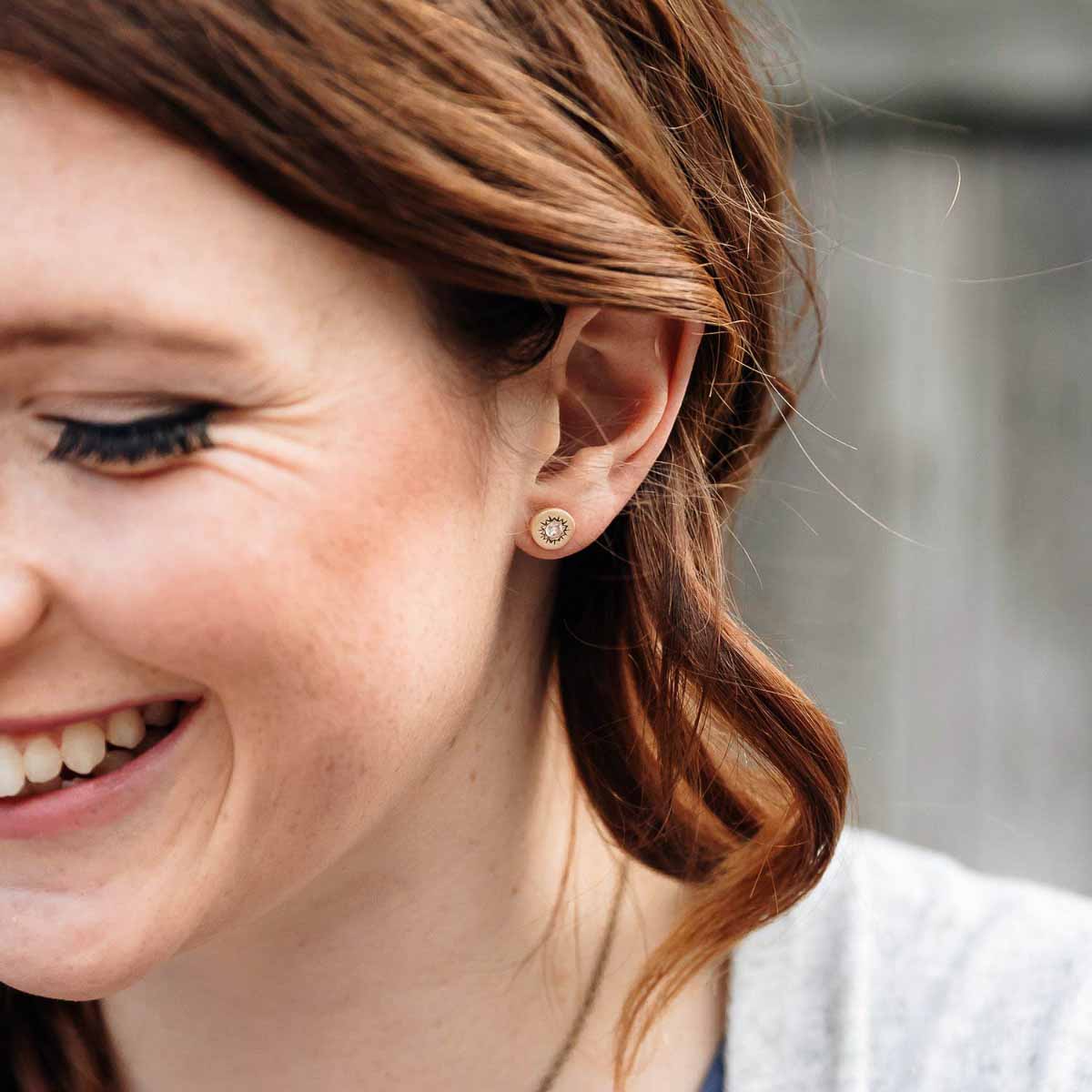 Girl wearing her 14k yellow gold sunburst stud earrings with a matte-brushed finish with 3mm crystals 