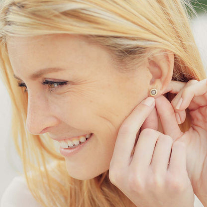 Girl wearing her 14k yellow gold sunburst stud earrings with a matte-brushed finish with 3mm crystals 