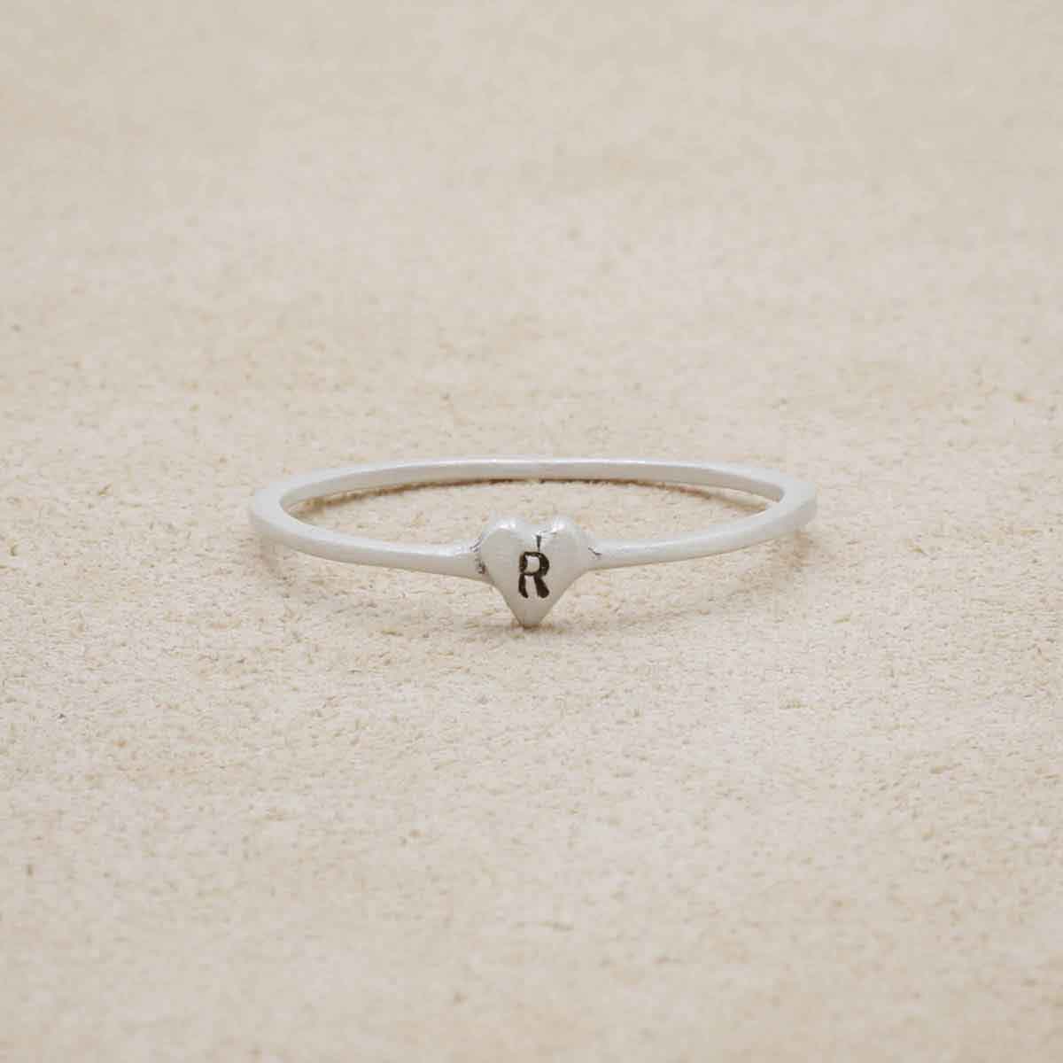 sterling silver Sweet Love Initial Ring - One Heart, personalized with an initial, on a beige background