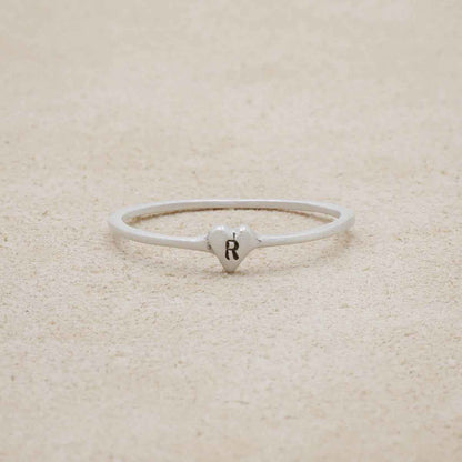 sterling silver Sweet Love Initial Ring - One Heart, personalized with an initial, on a beige background