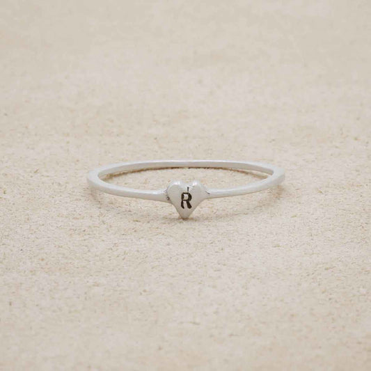 sterling silver Sweet Love Initial Ring - One Heart, personalized with an initial, on a beige background