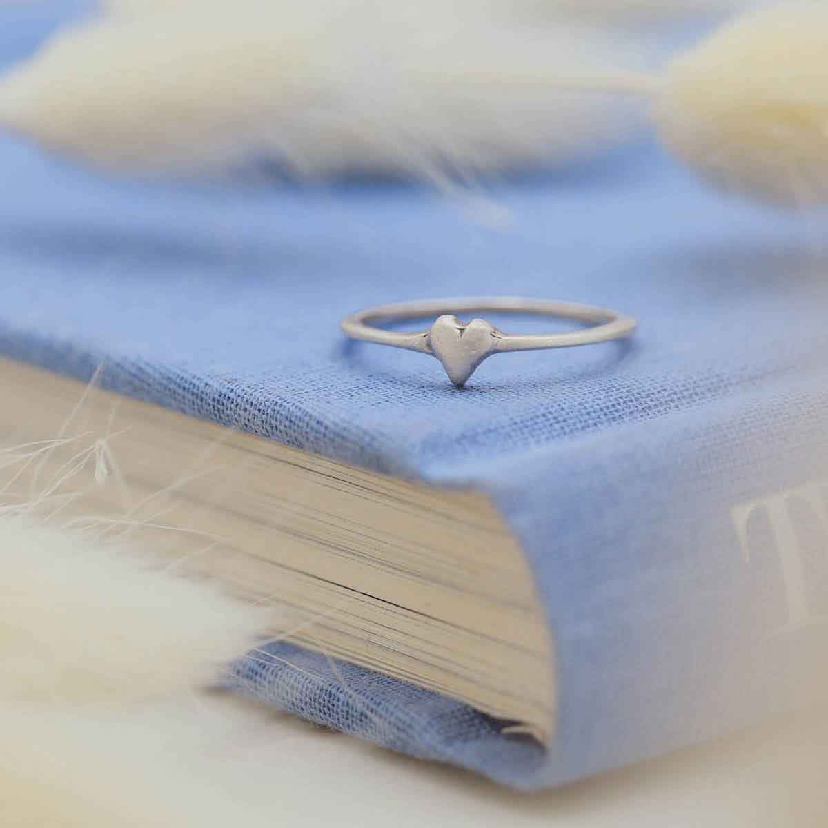 a sterling silver sweet love ring - one heart on a blue book