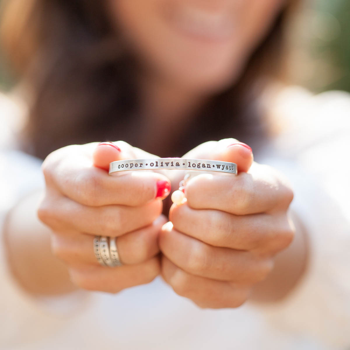 Woman displaying her sterling silver thin cuff personalized with names