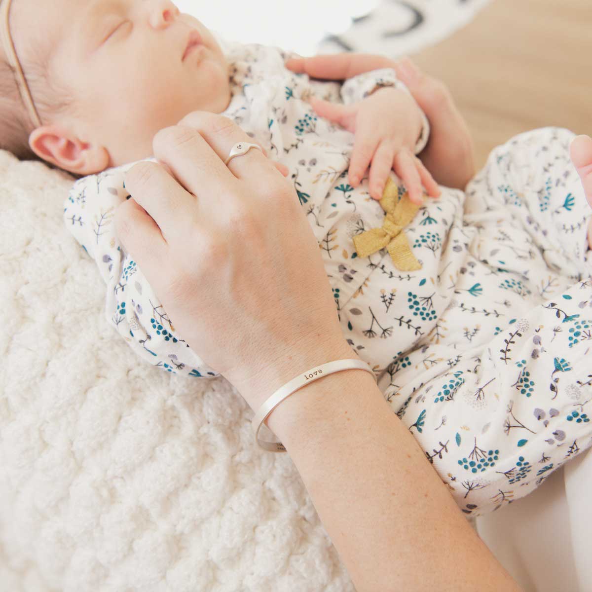 Woman holding her baby while wearing her thin sterling cuff