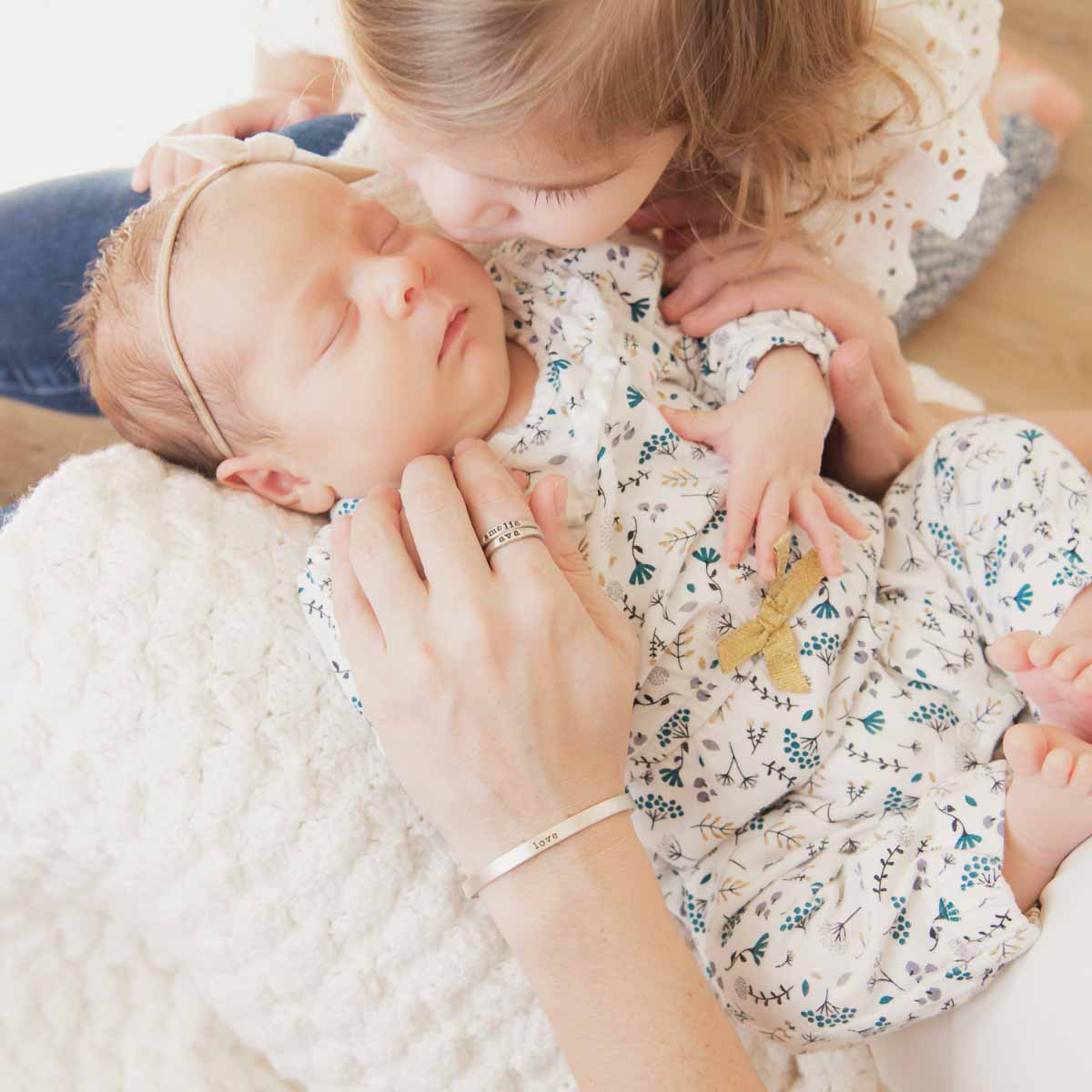 Woman holding her baby while wearing her thin sterling cuff