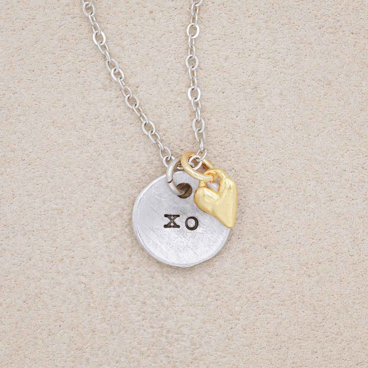 this is love necklace handcrafted in pewter with small gold plated heart charm, on beige background