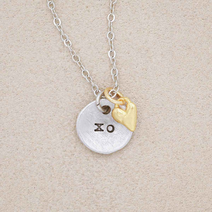 this is love necklace handcrafted in pewter with small gold plated heart charm, on beige background