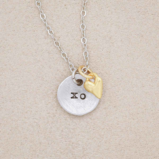 this is love necklace handcrafted in pewter with small gold plated heart charm, on beige background