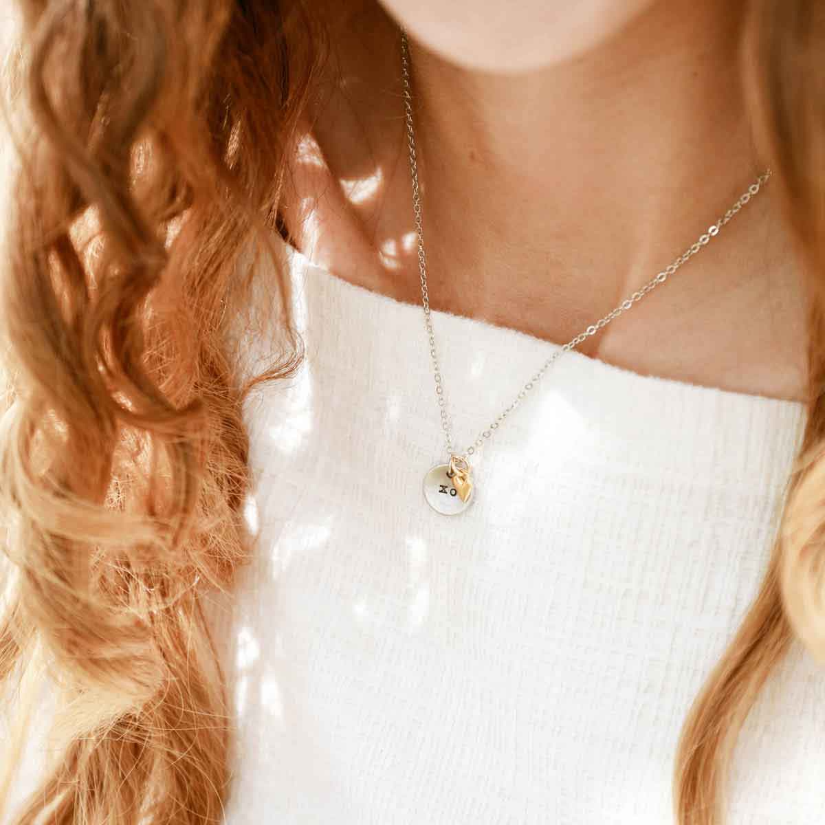 girl holding this is love necklace handcrafted in pewter with small gold plated heart charm