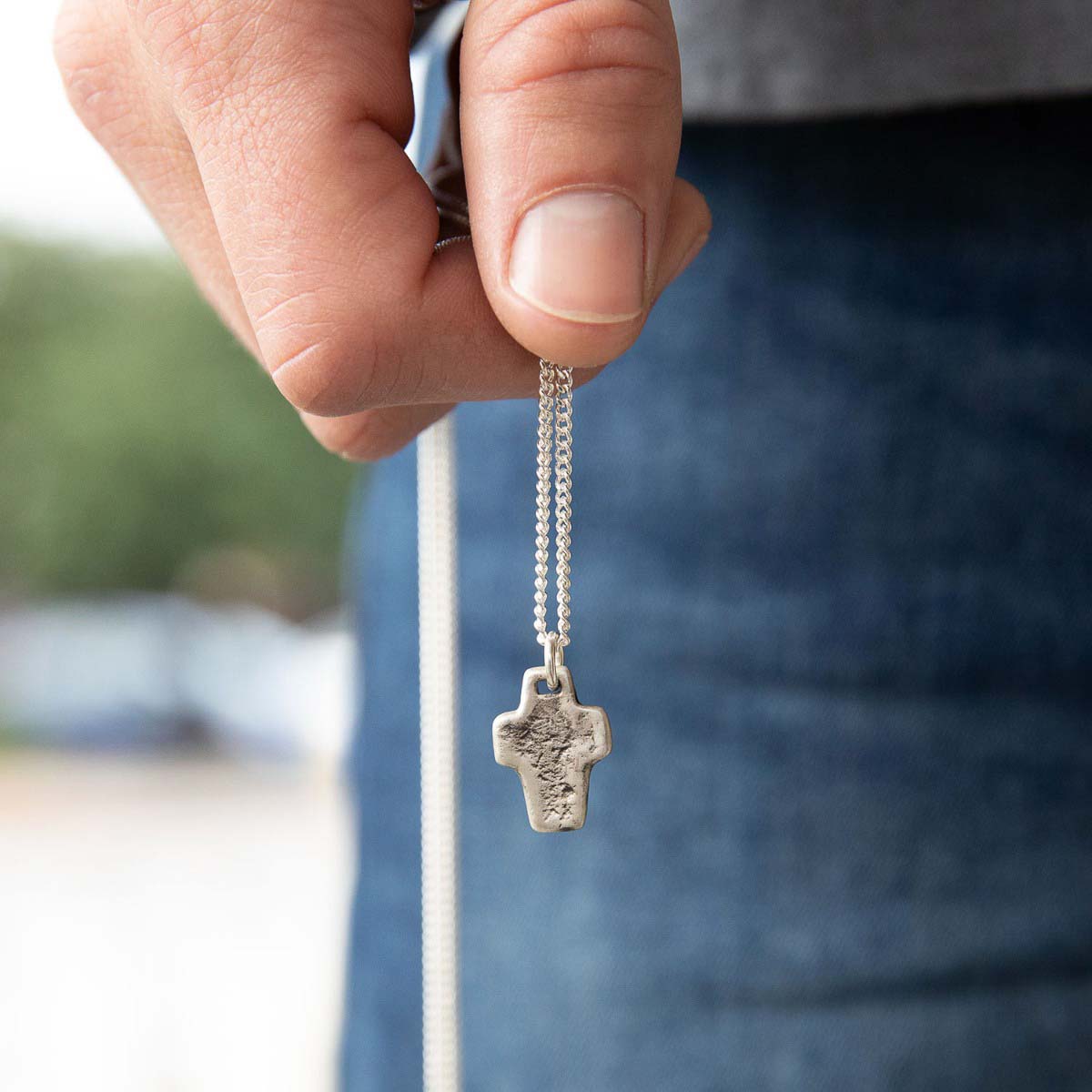 man holding a Thrive Cross necklace handcrafted in sterling silver with choice of chain