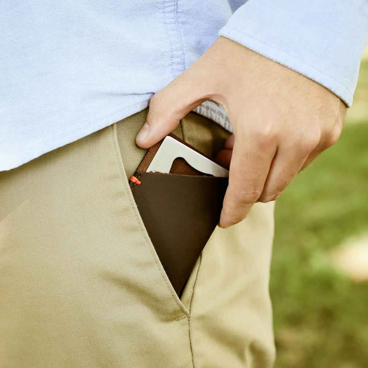 hand putting personalized Trailblazer Bottle Opener and Leather Wallet into pocket