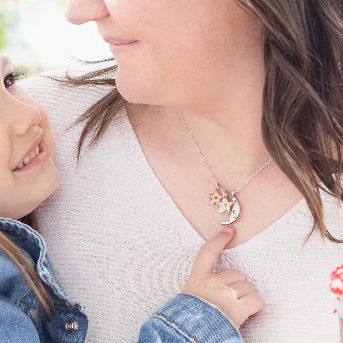 Woman wearing her Twinkle little stars necklace with sterling silver and bronze star and moon charms personalized with initials