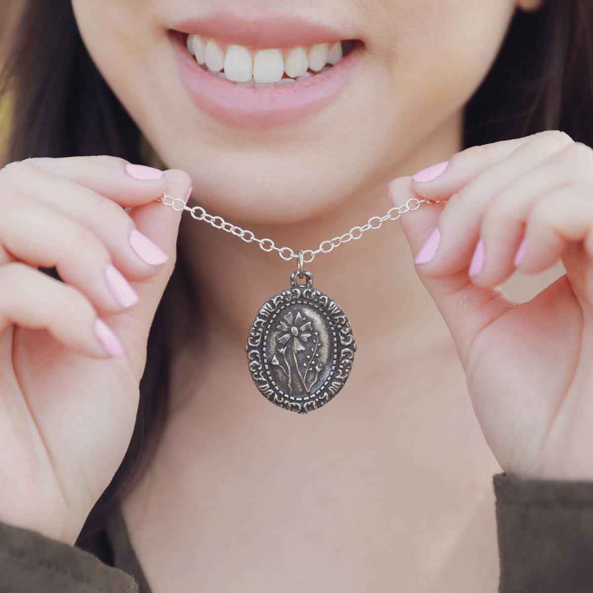 girl holding a pewter vintage cameo necklace