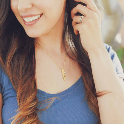 girl wearing her personalized 10k yellow gold what matters most necklace strung on a gold link chain with a freshwater pearl 