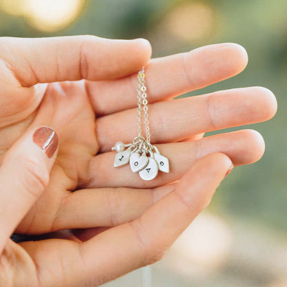 girl holding sterling silver wild about you initials necklace with personalized initial charms and tiny freshwater pearl