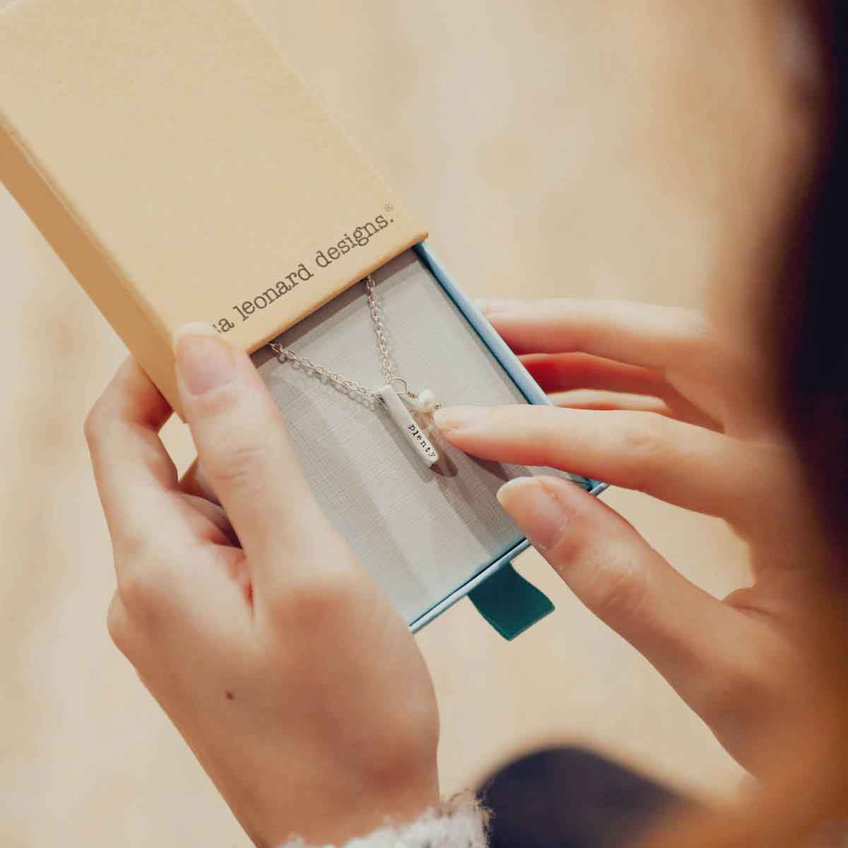 girl holding word of the year necklace in lisa leonard necklace box