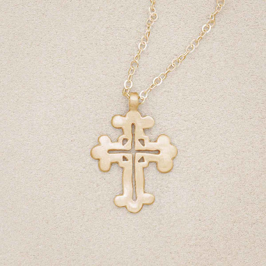 14k yellow gold work of art cross necklace, on beige background