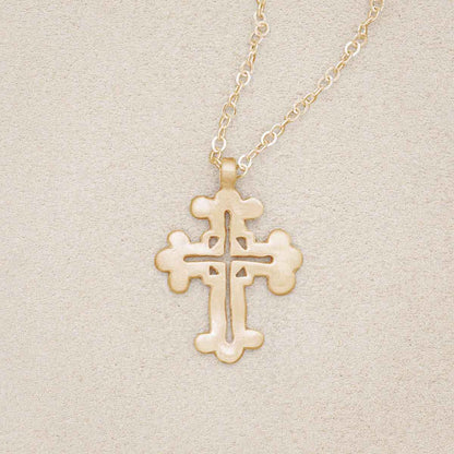 10k yellow gold work of art cross necklace, on beige background