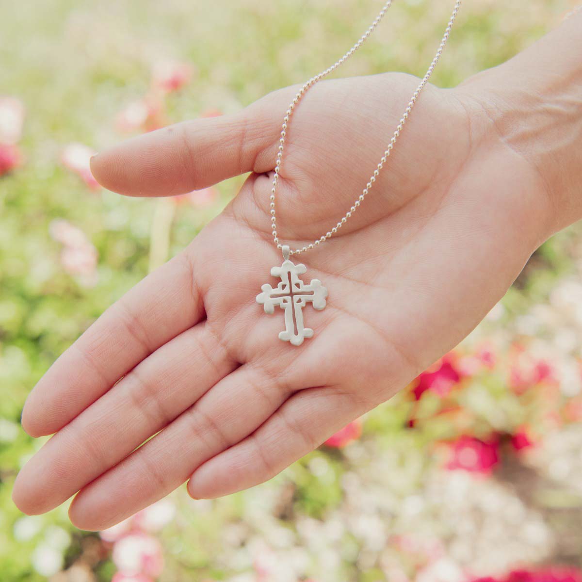 hand holding sterling silver work of art cross necklace 