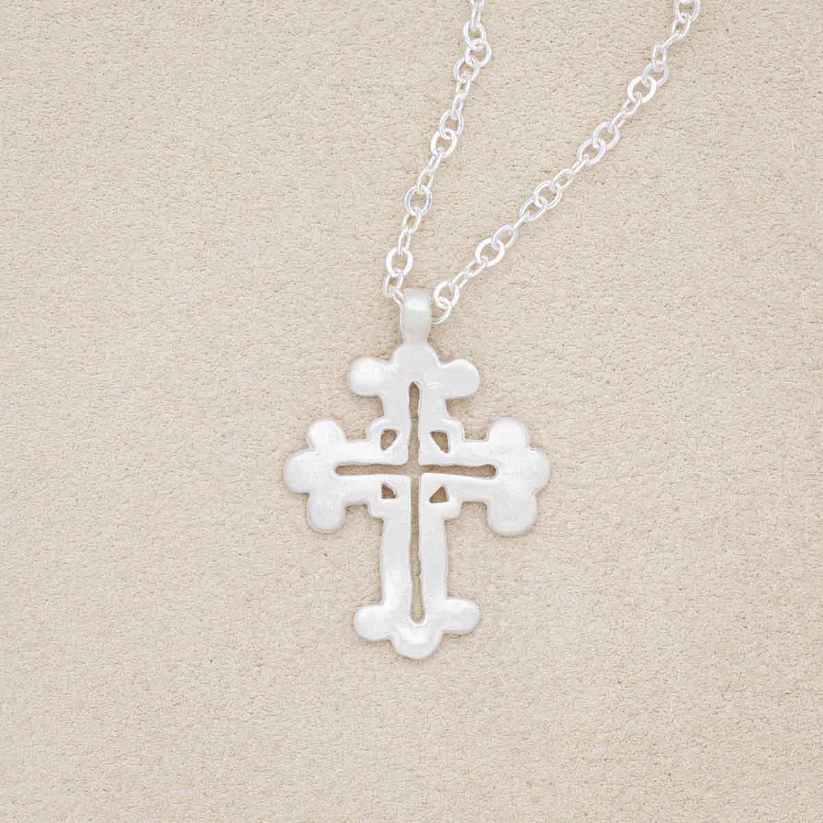 sterling silver work of art cross necklace on beige background