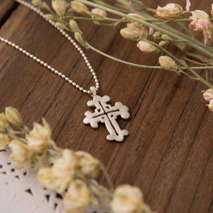 sterling silver work of art cross necklace on wood table