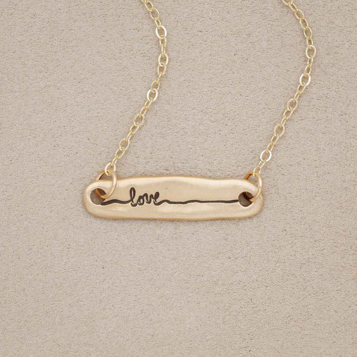 14k yellow gold written with love necklace, on beige background