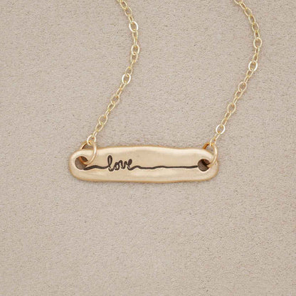 14k yellow gold written with love necklace, on beige background