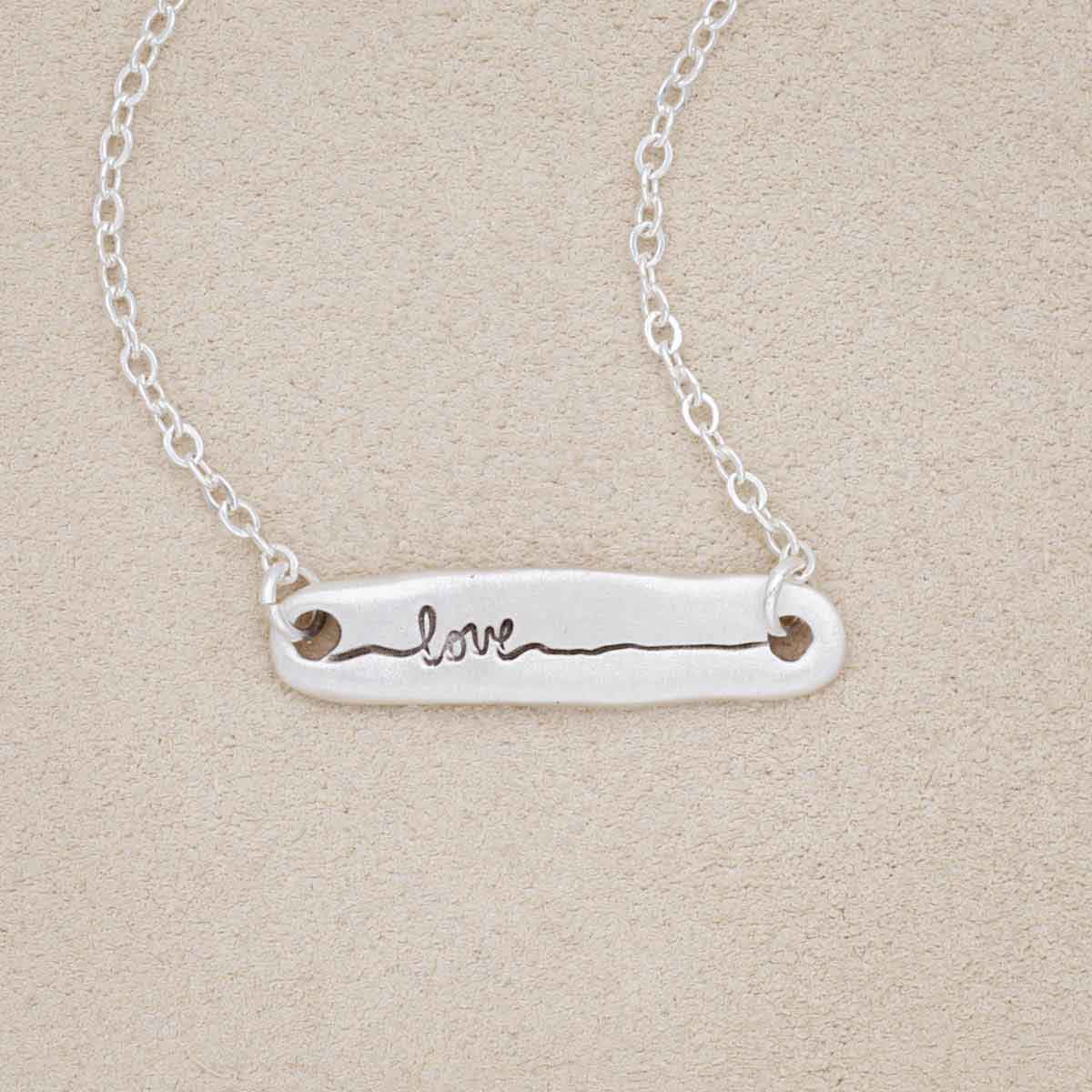 sterling silver written with love necklace, on a beige background