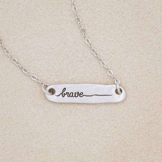 you are brave pewter necklace, on a beige background