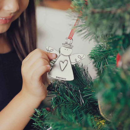 girl holding the you're my angel ornament on christmas tree