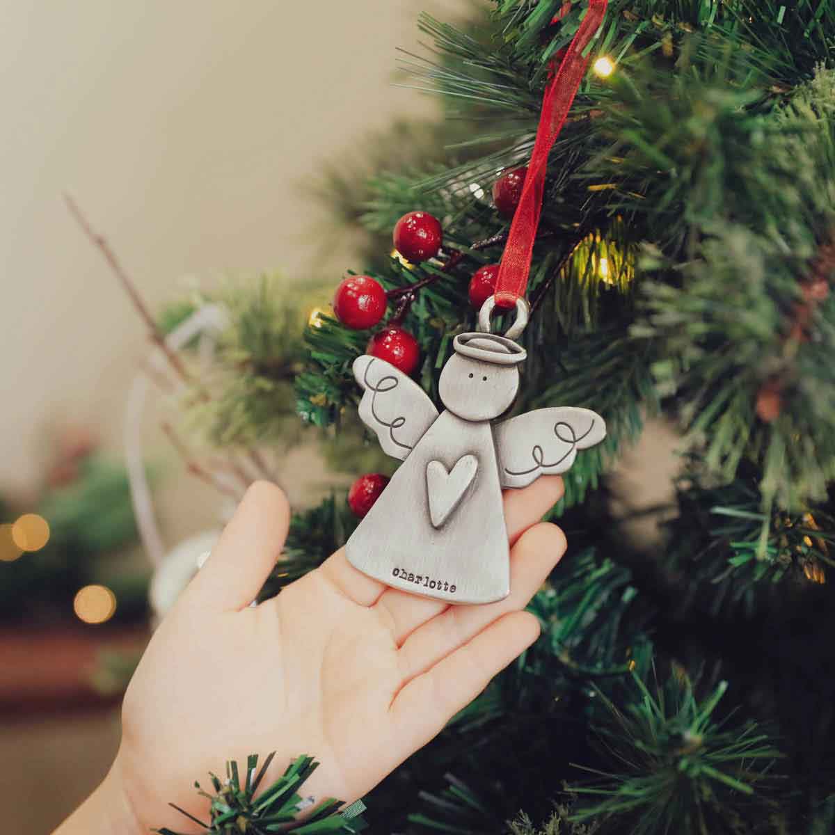 girl holding the you're my angel ornament on christmas tree