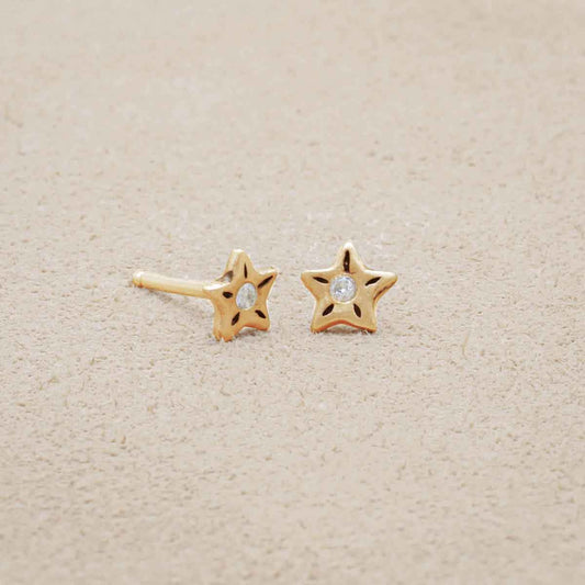 Your Spark Earrings, handcrafted in 14k yellow gold, set with a 1.5mm cubic zirconia, on beige background