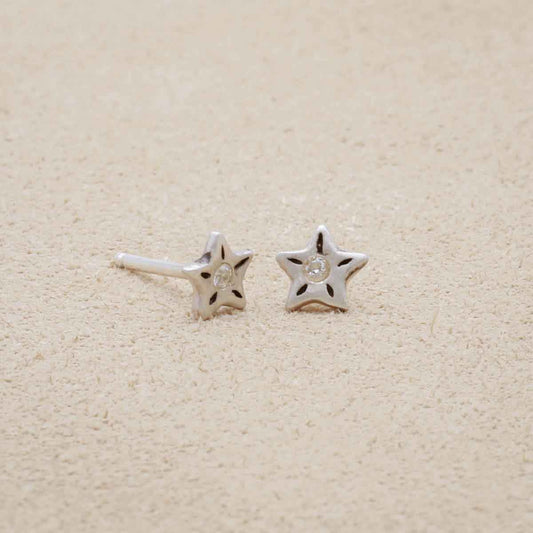 Your Spark Earrings, handcrafted in sterling silver, set with a 1.5mm cubic zirconia, sitting on beige background