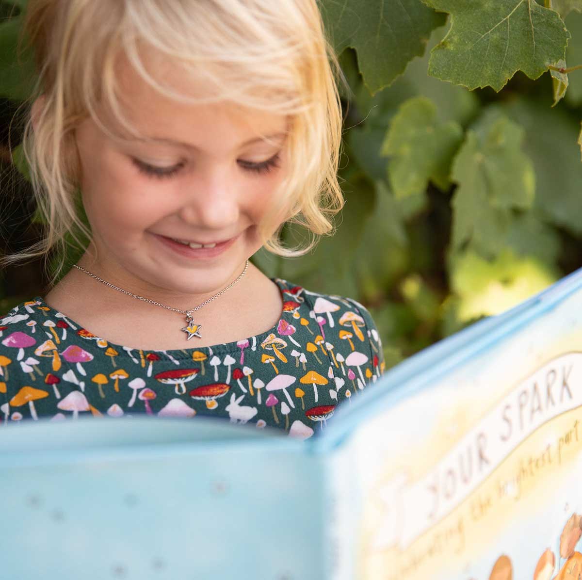 little girl holding your spark kids necklace